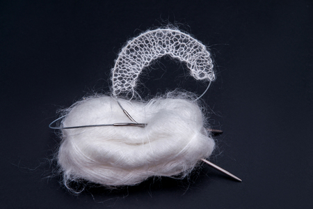balls of white yarn on a black background and knitting needles close-upの写真素材