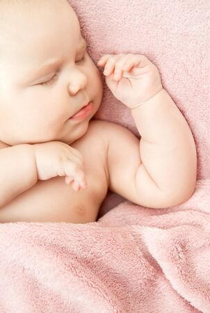 a small child sleeps in a bed under a pink blanket, verticalの写真素材