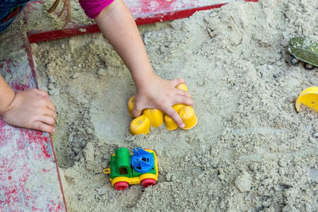 a child plays in the sandbox and makes an animal figure out of the sand