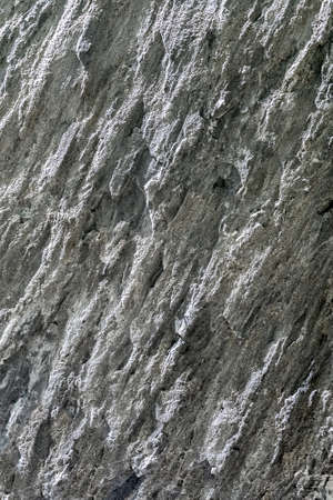 A vertical fragment of rock. Natural stone texture.