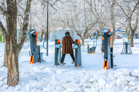 A woman trains on a simulator on a sports field on a frosty day. An active lifestyle of an elderly person.の写真素材