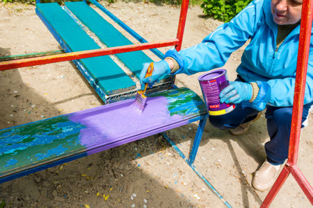 A woman paints a bench on the playground in kindergartenの写真素材