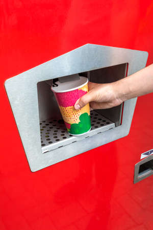 A man pours carbonated water from a vending machine into a paper cup. Retro vending machine for sparkling waterの写真素材