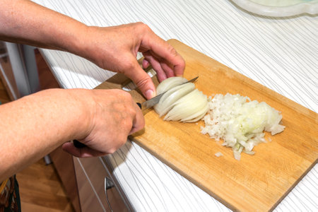 A woman cuts onions in the kitchen to cook a homemade dinnerの写真素材