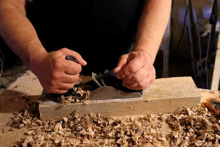 Hands with a tool on the background of a carpentry workshop. Photo in high quality.