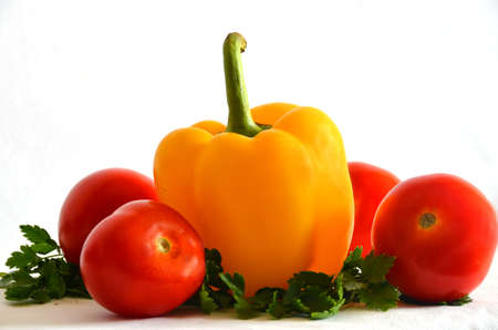 red and yellow peppers, red tomatoes and green parsley on a white backgroundの写真素材