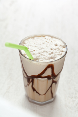White Frappe Coffee Glass with iced drink on a light wooden table.の写真素材