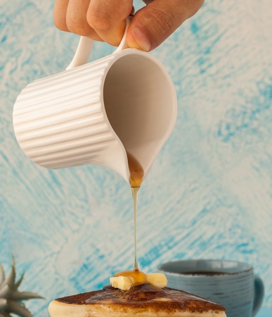 Pancakes stack pouring marple syrup. Little jug. Breakfast. coffee cup. side view
