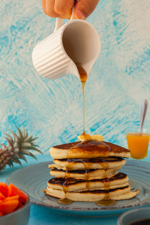 Pancakes stack pouring marple syrup. Little jug. Breakfast. Jem, Papaya. side viewの写真素材