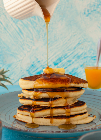 Pancakes stack pouring marple syrup. Little jug. Breakfast. Jem, Papaya. side viewの写真素材