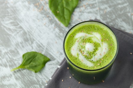 Fresh green spinach smoothie in a glass cup with yogurt on a gray wooden surface. Flat layoutの写真素材