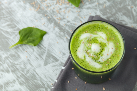 Fresh green spinach smoothie in a glass cup with yogurt on a gray wooden surface. Flat layoutの写真素材