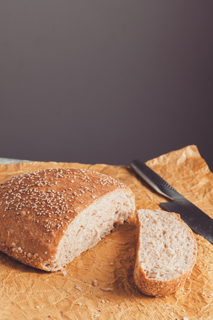 Freshly baked loaf of wholemeal bread with bran on baking paper. Sliced by knifeの写真素材