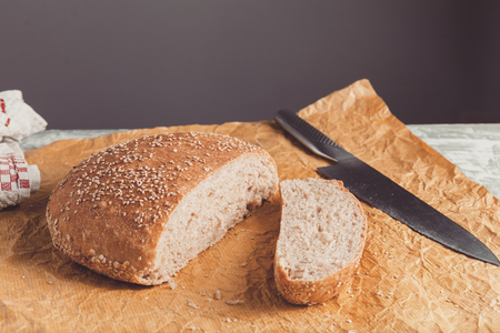 Freshly baked loaf of wholemeal bread with bran on baking paper. Sliced by knifeの写真素材