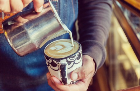 Professional barista pouring latte foame tulip over coffee, espresso and creating a perfect cappuccinoの写真素材