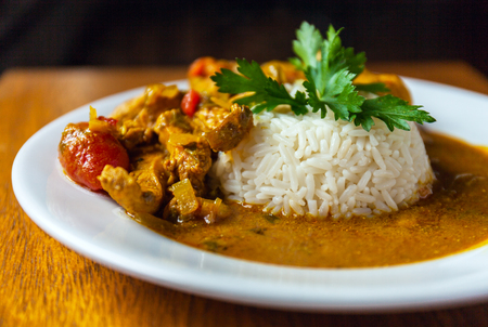 Curry chicken bright juicy with white rice on plate over wooden background. side view.の写真素材