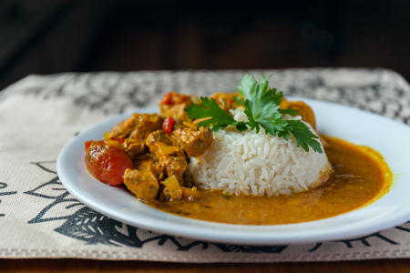 Curry chicken bright juicy with white rice on plate over the tablecloth background. side view.の写真素材