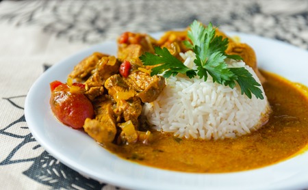 Curry chicken bright juicy with white rice on plate over the tablecloth background. side view.の写真素材