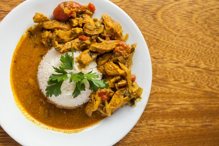 Curry chicken bright juicy with white rice on plate over wooden background. Top view, flat lay.の写真素材