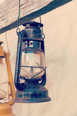 Kerosene lamp or lantern weighs on a wooden beam. verticallyの写真素材