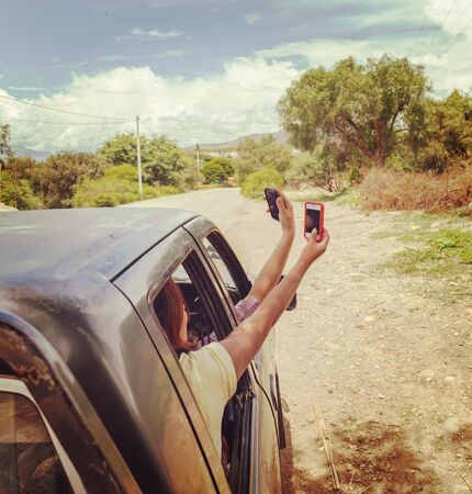 Passengers of the car far from civilization are looking for a mobile phone network signal. No connectionの写真素材