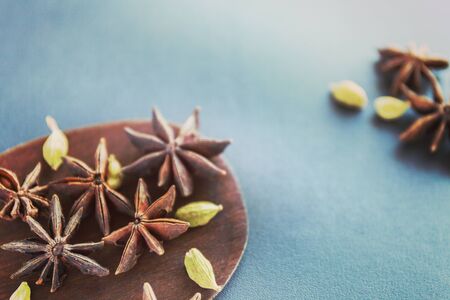 Dry Star anise and cardamom on a brown wooden spatula. Natural food spices and seasonings. Tasty eating. Close-up.の写真素材