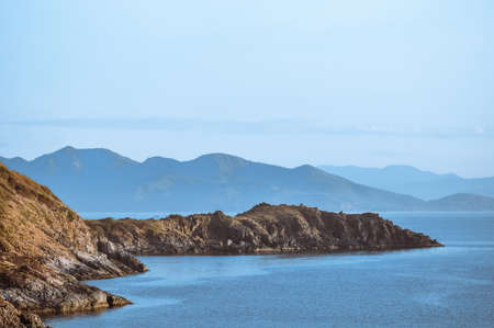Embossed rocks in the sea against the background of mountainsの写真素材