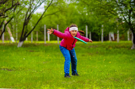 girl throws a disc on a green lawnの写真素材