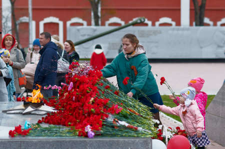 BLAGOVESHCHENSK, RUSSIA - MAY 9, 2021: Russian people of different generations lay flowers at the eternal flame, a symbol of the people's memory of the fallen heroes, for the honor of the Motherland.のeditorial素材