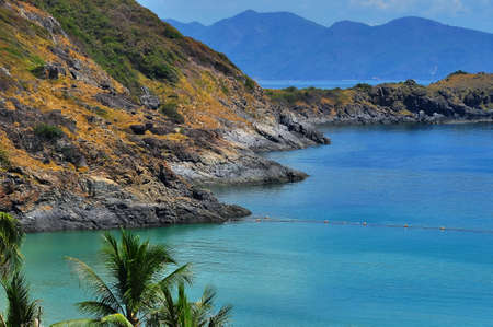 Seascape with rocks in the bay of Vinperl island, Nha Trang, Vietnam. Palm leaves in the foreground and buoys on turquoise water.の写真素材