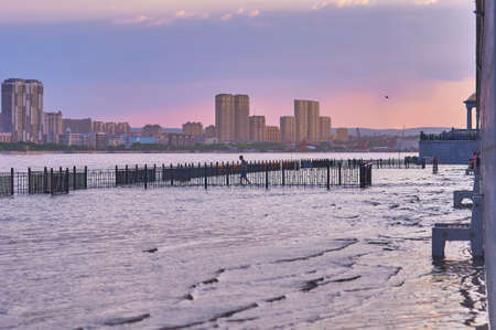 BLAGOVESHCHENSK, RUSSIA - JUNE 21, 2021: The lower tier of the Embankment with railings and benches. Flood of the Amur River.のeditorial素材