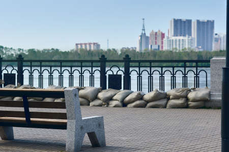 View of the Chinese coast from the flooded embankment of the city of Blagoveshchensk, Russia. Flood of the Amur River. Selective focus, distant shore blurred. Sandbag barrier under the fence.の写真素材