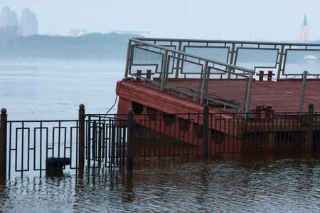 Blagoveshchensk, Russia. Pontoon floating pier, tied to the embankment during floods. The increased water level in the river in an early foggy morning. In the background in blur The Chinese city of Heihe.の写真素材