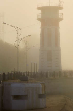 Long-term Firing Point and lighthouse in a tight strong fog. Urban embankment early in the morning. Blagoveshchensk, Russia. Border with China.の写真素材