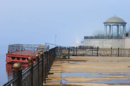 A lighthouse, a rotunda with a balustrade and a pontoon pier on the embankment of the city of Blagoveshchensk, Russia. Morning fog.の写真素材