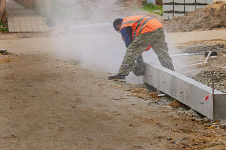 A worker cuts a curb with a circular saw at a construction site.の写真素材