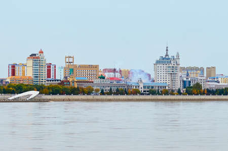 Autumn view of the embankment of Heihe city, China, from the city of Blagoveshchensk, Russia. Smoke from firecrackers exploding over buildings.の写真素材