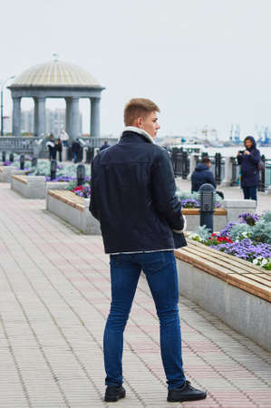 The guy in jeans and a leather jacket on the background of the rotunda in blur. View from the back.の写真素材