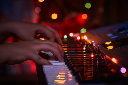 Christmas synthesizer on a dark background under the light of an electric garland. Close-up. The...