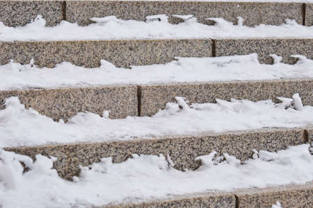 Snow on the steps of the granite stairs. Descent from the city embankment.の写真素材