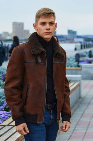 Portrait of a young Caucasian blond guy in a warm leather brown jacket. Skin acne.の写真素材