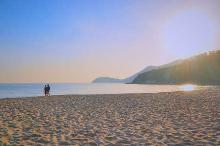 An island in Vietnam. White sand, sea, mountains, palms, two people in the evening before sunset.の写真素材