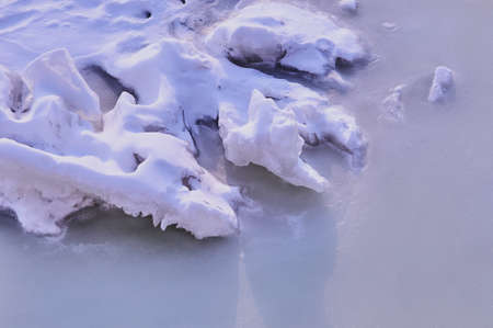 Pieces of ice covered with white snow on a frozen river. Winter background texture.