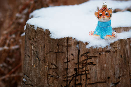 Christmas toy of a tiger cub on a stump damaged by insects. Happy New Year 2022. Tiger symbol of 2022. Wood texture. Selective focus.の写真素材