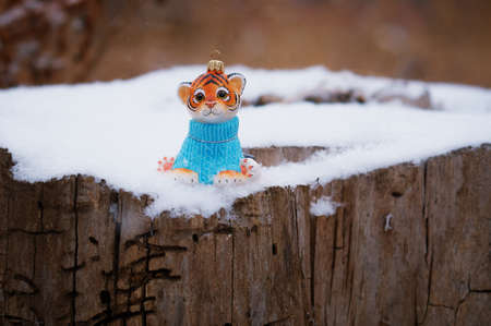Christmas toy of a tiger cub on a stump damaged by insects. Happy New Year 2022. Tiger symbol of 2022. Wood texture. Selective focus.の写真素材