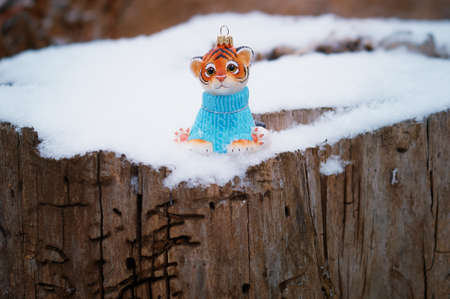Christmas toy of a tiger cub on a stump damaged by insects. Happy New Year 2022. Tiger symbol of 2022. Wood texture. Selective focus.の写真素材