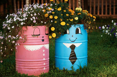 Two barrels painted with paints with flowers. Secondary use. The idea of landscape design. Summer evening in the school yard.の写真素材