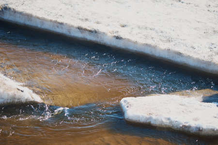 Melting ice on the river in spring. Ice drift time. Natural structure. Needles in the sun.