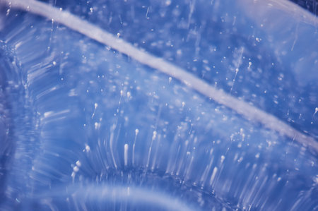 Air bubbles rising from the bottom frost in transparent blue ice. Ice pattern and texture. Optical distortion and refraction of light.の写真素材