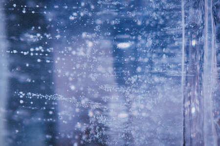 Air bubbles rising from the bottom frost in transparent blue ice. Ice pattern and texture. Optical distortion and refraction of light.の写真素材